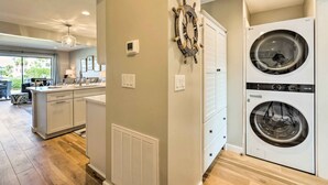 A modern kitchen with a central island, a double-door laundry room, and a view of the outdoors. - St Helena Island Condo w/ Pool & Beach Access! (Harbor Island)
