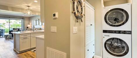 A modern kitchen with a central island, a double-door laundry room, and a view of the outdoors.