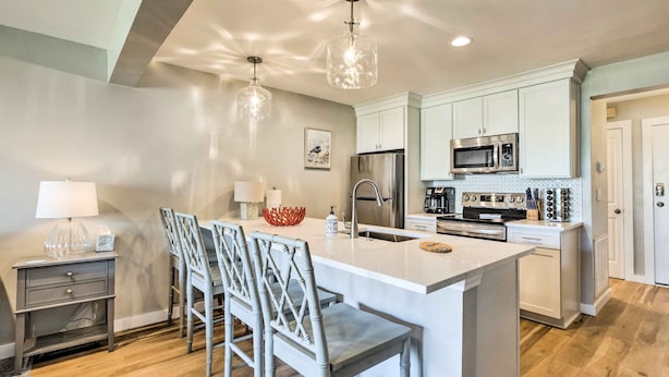 A modern kitchen with a central island, bar stools, a refrigerator, a microwave, and a sink. - St Helena Island Condo w/ Pool & Beach Access! (Harbor Island)