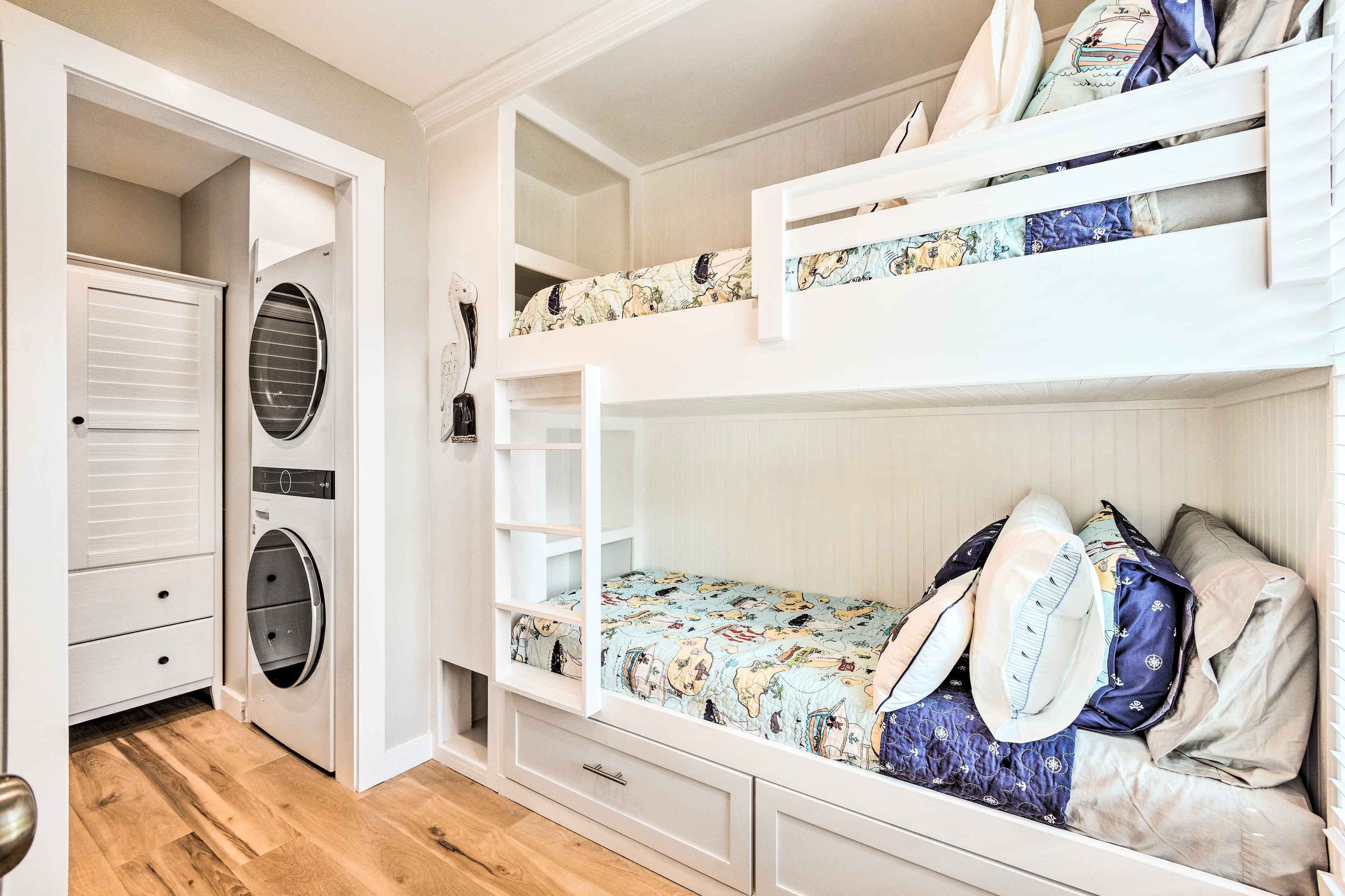 A bunk bed with a patterned mattress, a washing machine, and a white wardrobe in a compact room.