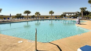 A swimming pool with clear blue water, surrounded by lounge chairs and palm trees. - St Helena Island Condo w/ Pool & Beach Access! (Harbor Island)