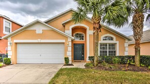 A two-story house with a garage, a front door, and a small front yard with a palm tree and shrubs. - Retreat w/ Pool: 25 Mi to Disney (Kissimmee)