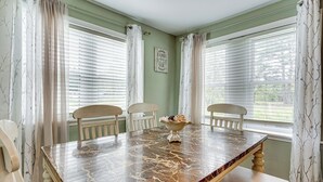 Comedor con una mesa de mármol, sillas blancas y un cuenco de fruta.