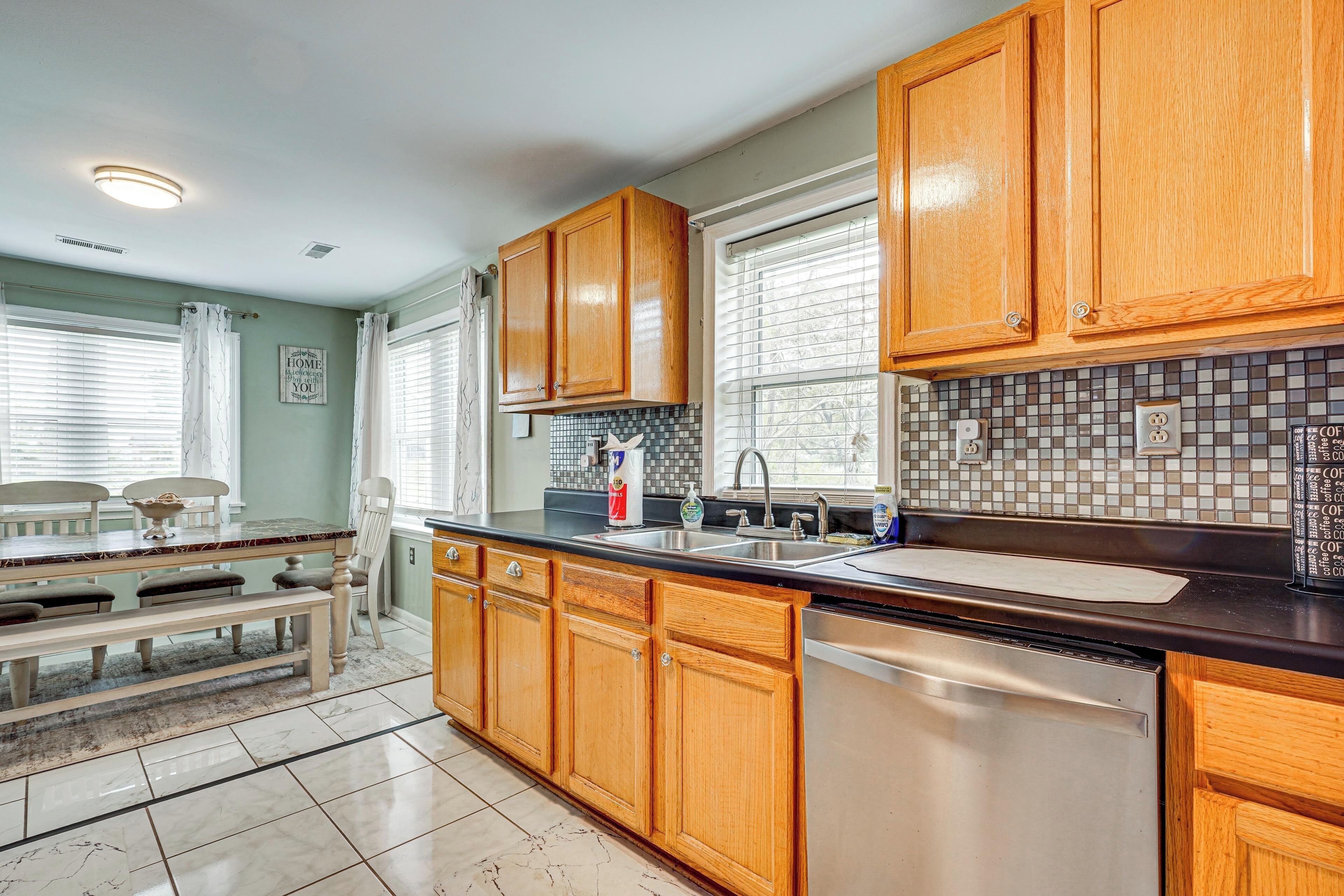 A kitchen with wooden cabinets, a stainless steel dishwasher, and a tiled backsplash.