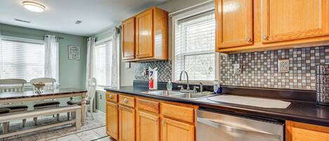 A kitchen with wooden cabinets, a stainless steel dishwasher, and a tiled backsplash.