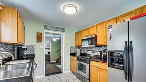 Una cocina con armarios de madera, un refrigerador de acero inoxidable, un microondas y una estufa.