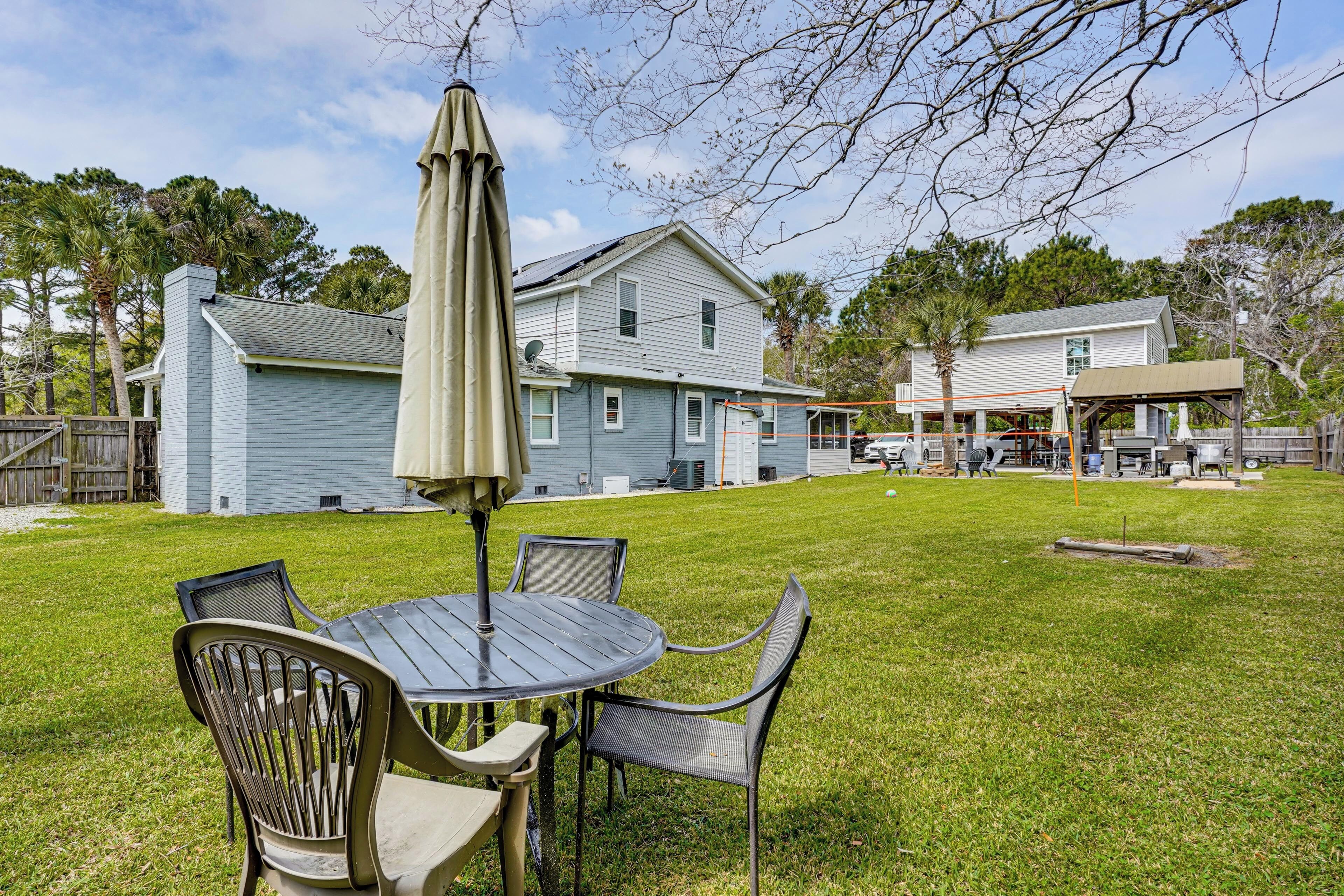 A backyard with a table and chairs, a covered umbrella, and a house in the background.