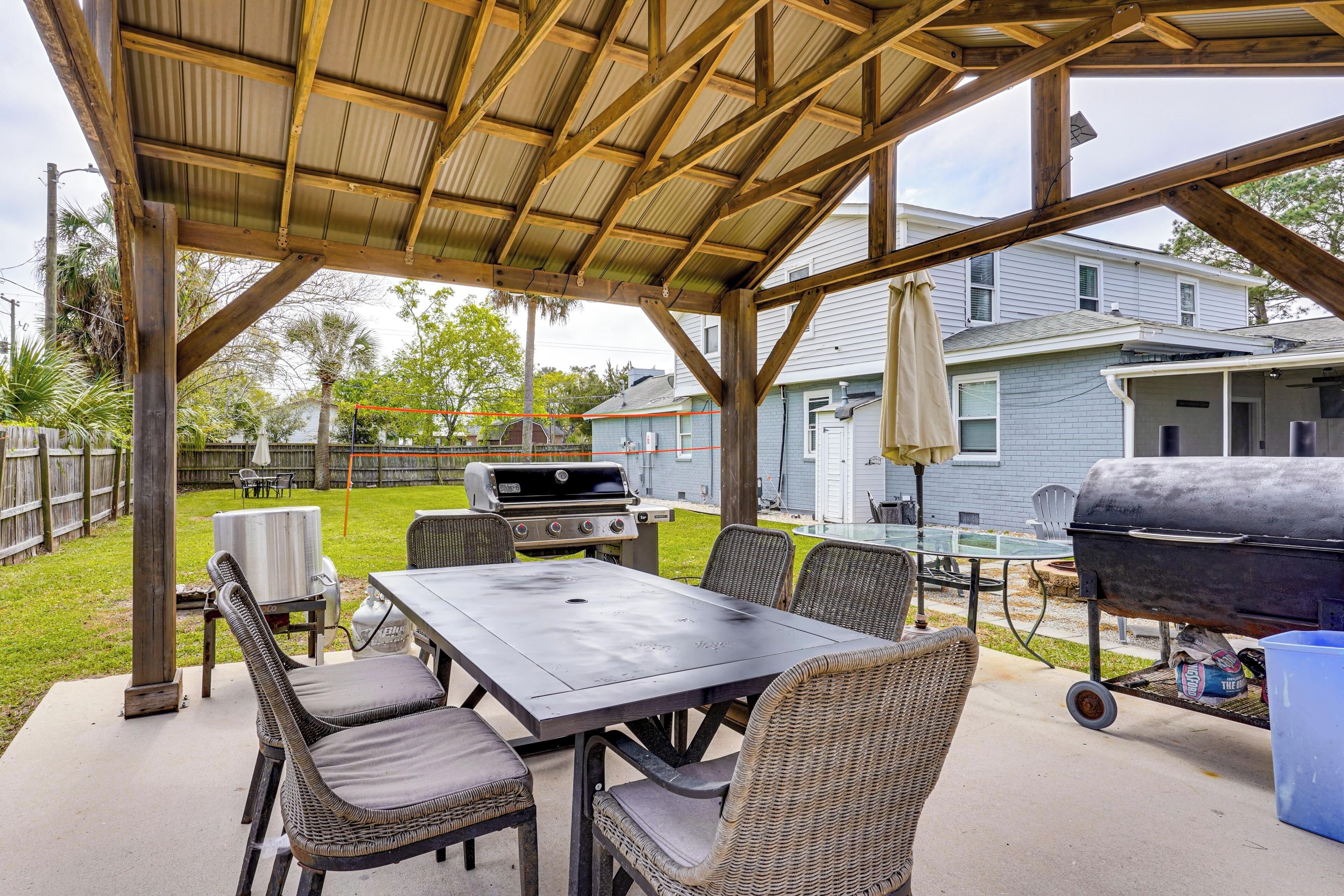 A covered patio with a grill, table, and chairs.