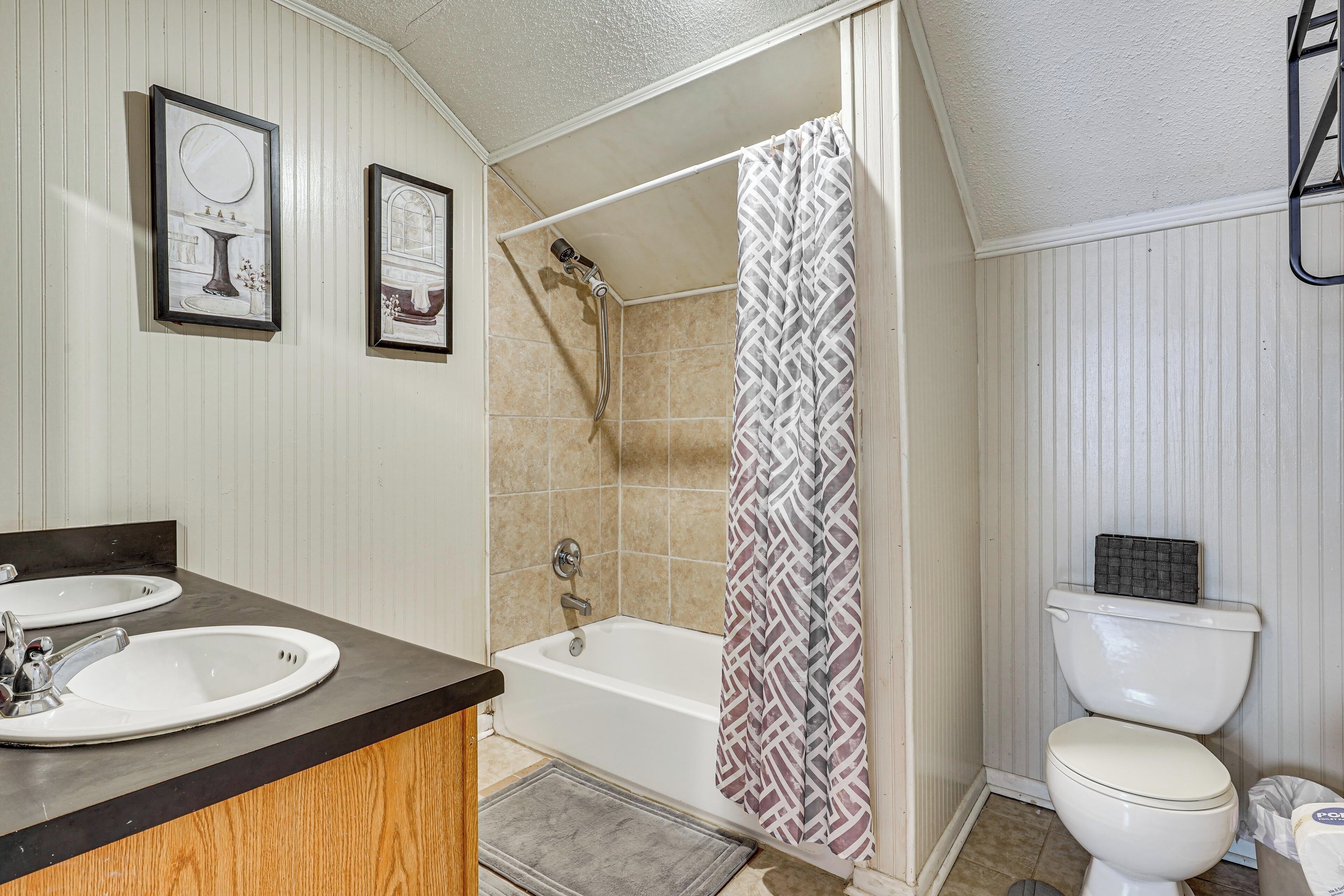 A bathroom with two sinks, a bathtub, and a toilet.