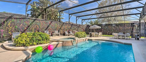 A swimming pool with a covered area, surrounded by lounge chairs and a patio.