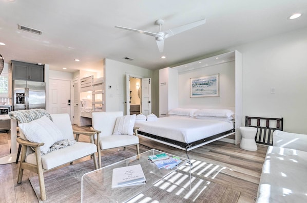 A modern hotel room with a bed, a sofa, a coffee table, and a ceiling fan.