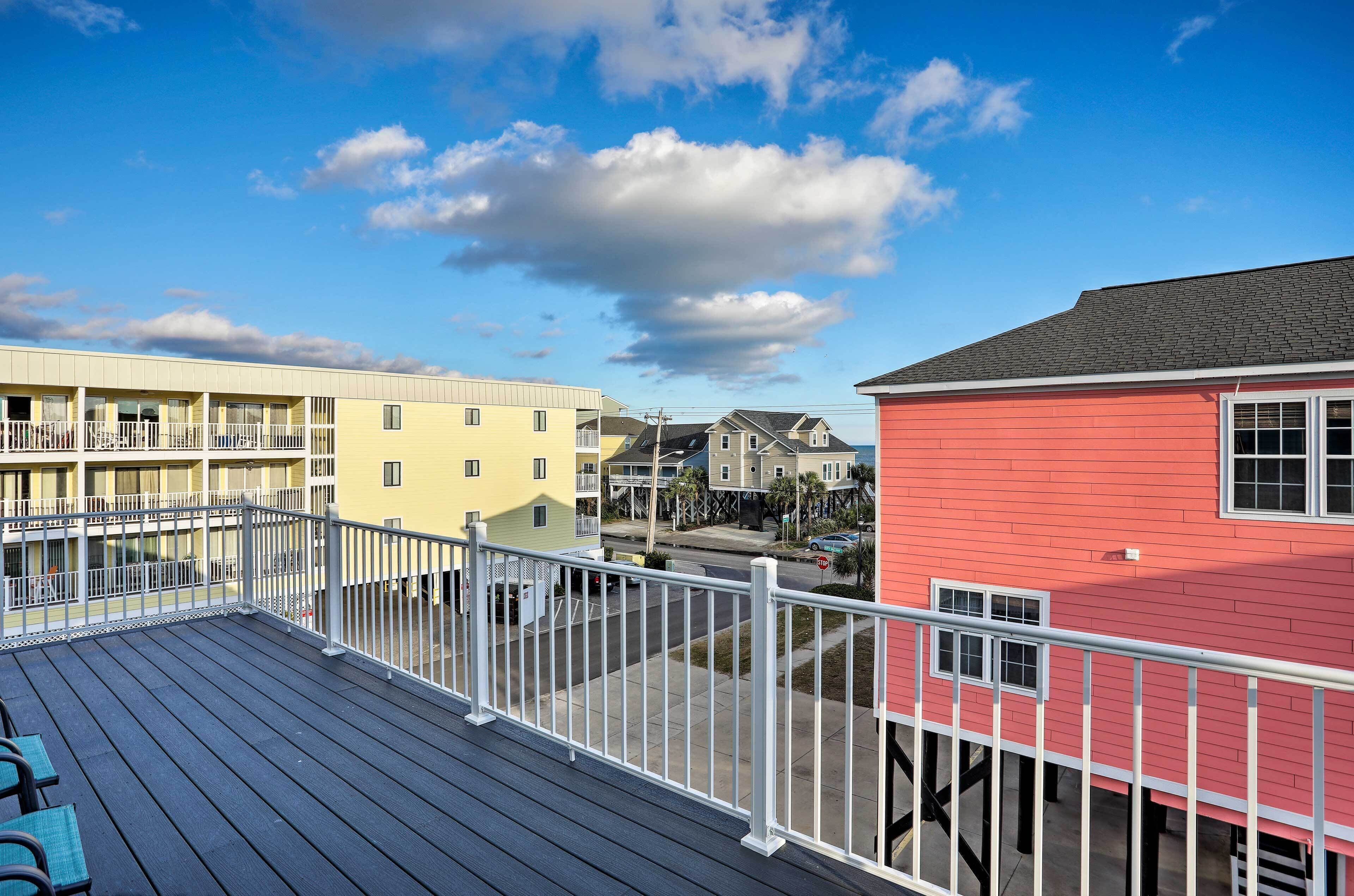 A balcony with a view of neighboring buildings, including a red house and a yellow building with a balcony.