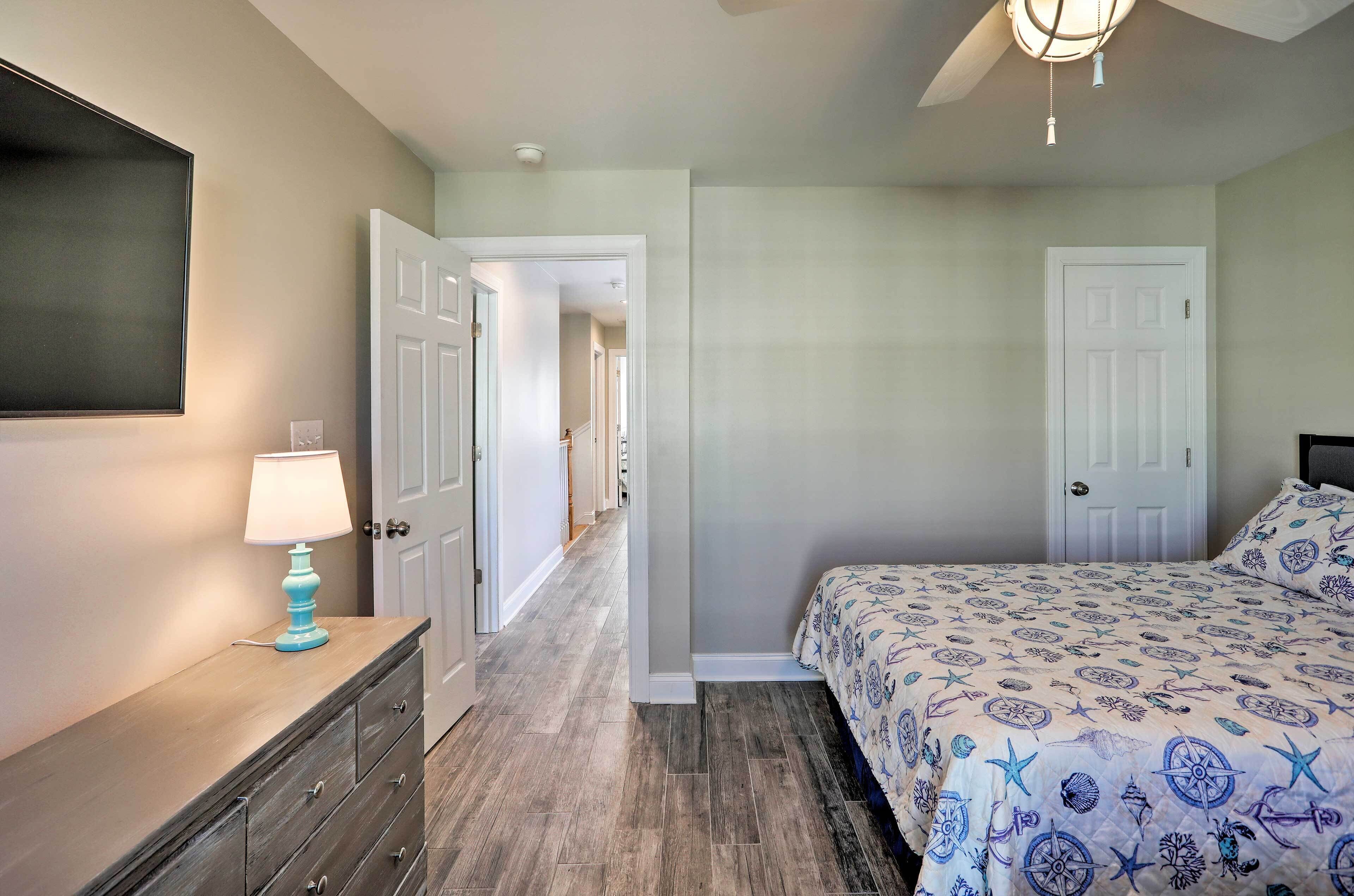 A bedroom with a bed, dresser, and a TV on the wall.