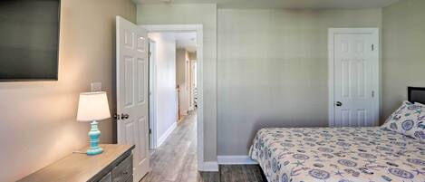 A bedroom with a bed, dresser, and a TV on the wall.