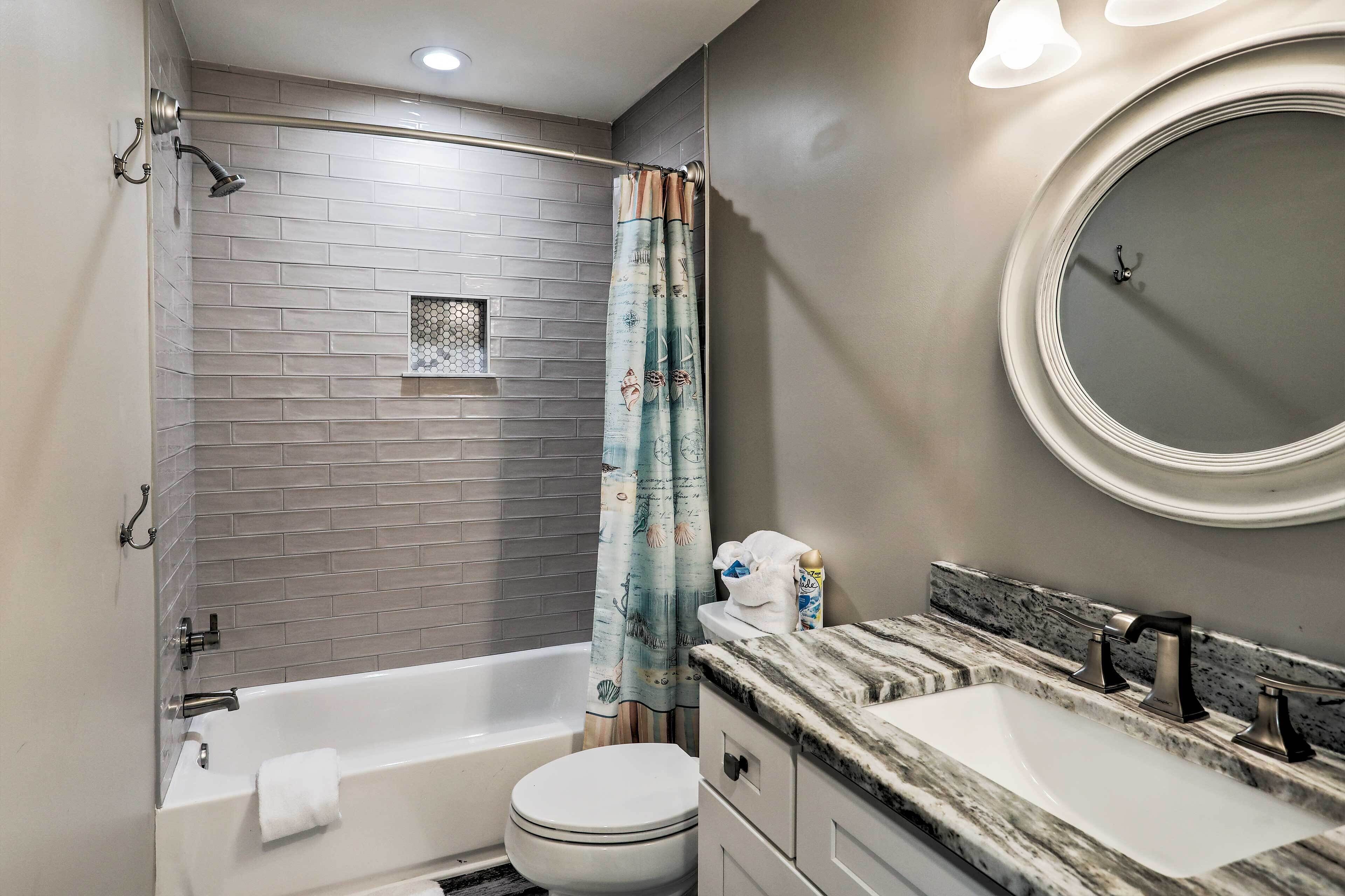 A modern bathroom with a bathtub, toilet, and two sinks.