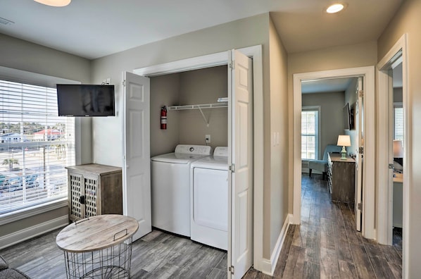 A laundry room with a washing machine, dryer, and a small table.