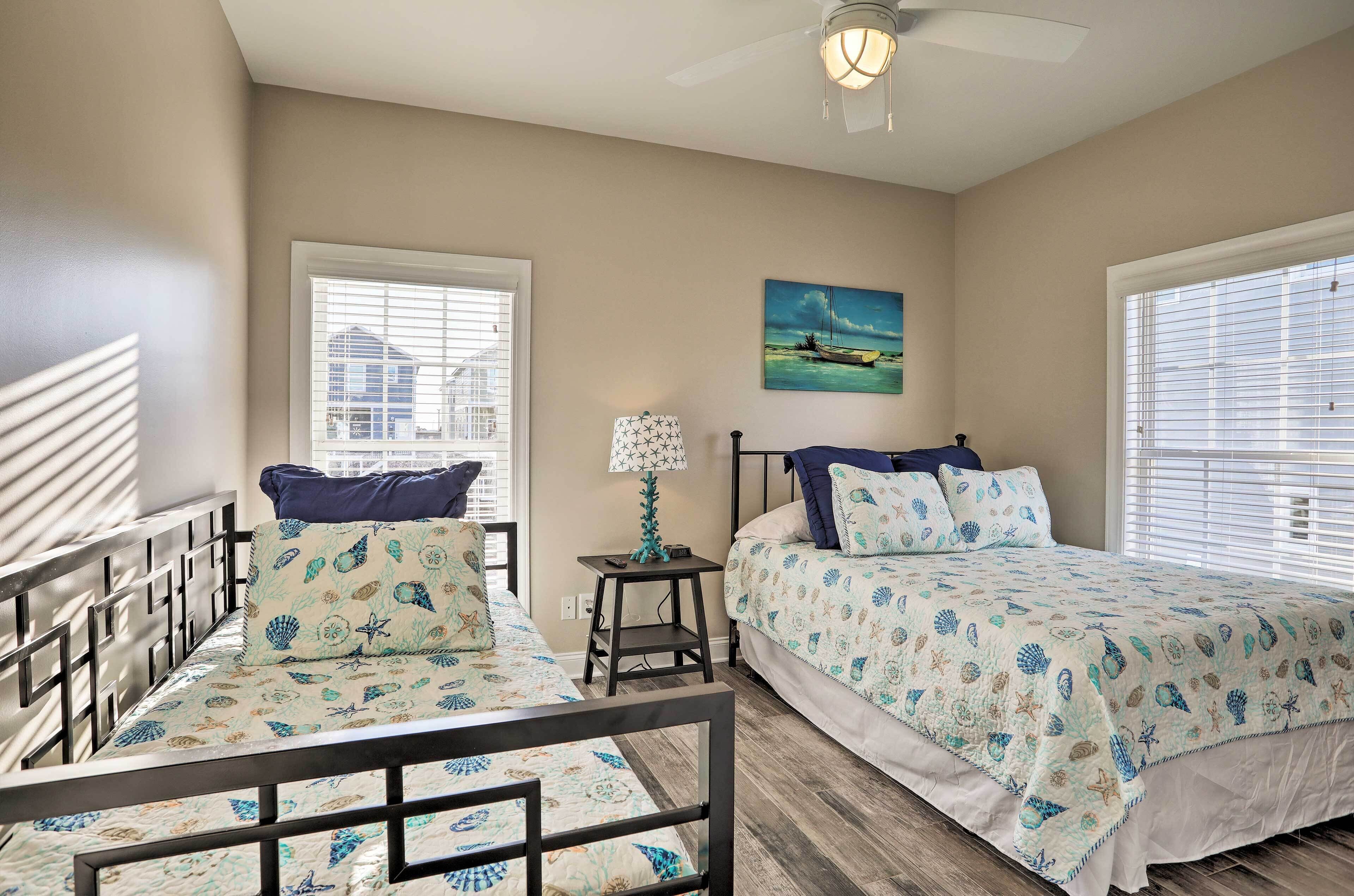 A bedroom with two beds, a standing lamp, and a ceiling fan.