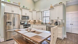 A modern kitchen with white cabinets, stainless steel appliances, and a wooden dining table.