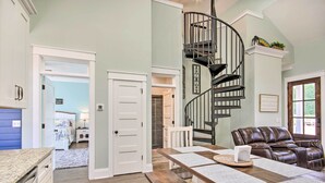 A spacious living area with a dining table, a leather sofa, and a spiral staircase.