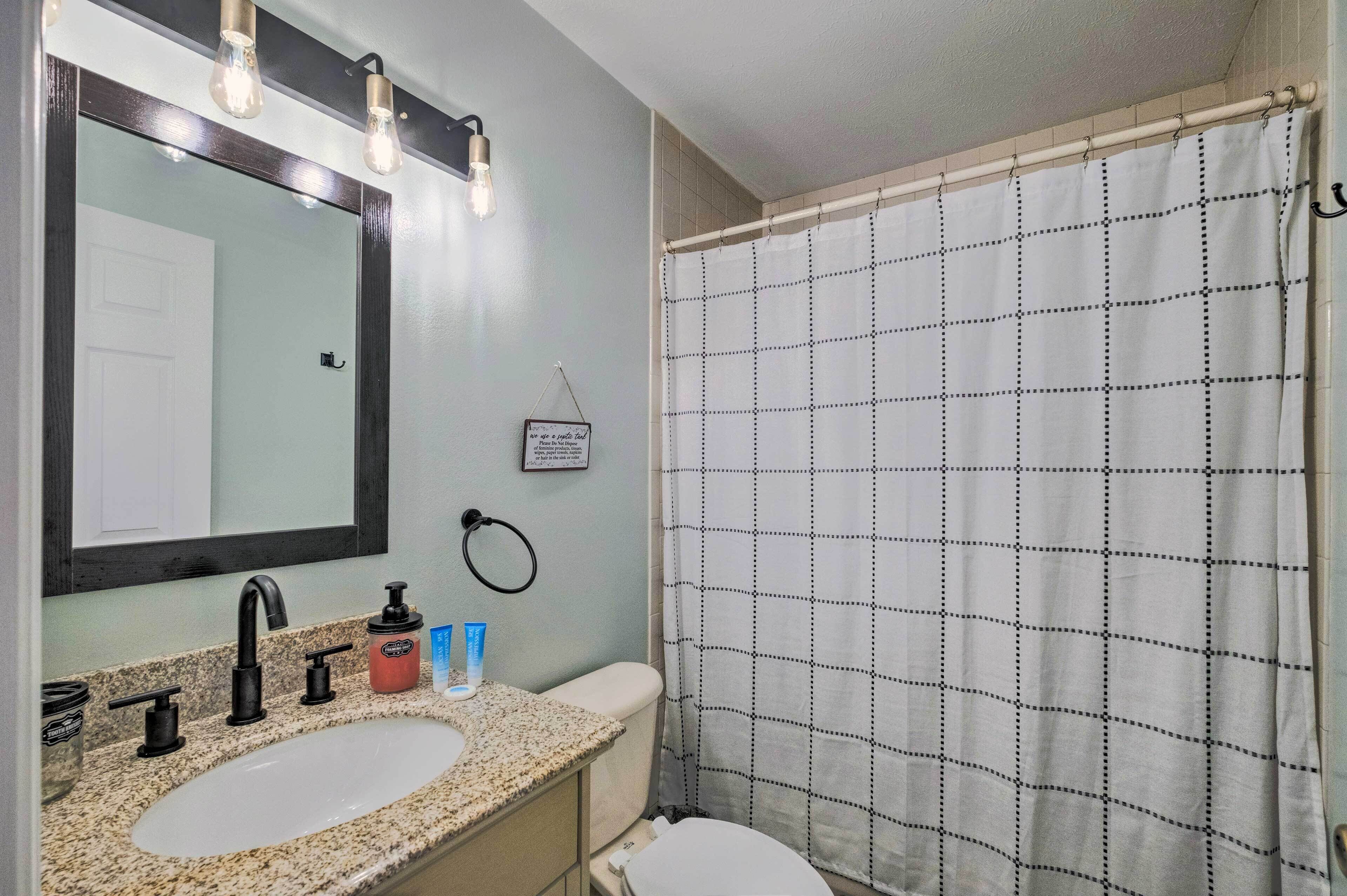 Un bagno con lavandino, specchio e tenda da doccia.