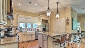 Una cocina amplia con una isla central, suelo de madera e iluminación colgante.