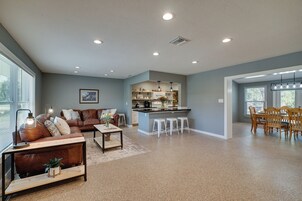 Uma sala de estar ampla com um sofá de couro marrom, uma mesa de centro e um espaço de jantar com cadeiras de madeira e uma mesa.