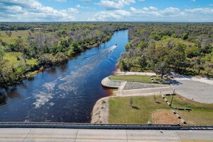 Um rio com um barco, cercado por vegetação e uma área de estacionamento com um edifício.