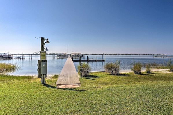 A grassy area with a paved walkway leading to a dock over water.