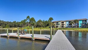 A waterfront hotel with a dock, outdoor seating, and a building with multiple balconies. - Stylish Bayfront Townhome < 10 Mi to Beach! (Mary Esther)