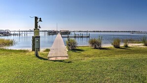 A grassy area with a paved walkway leading to a dock over water. - Stylish Bayfront Townhome < 10 Mi to Beach! (Mary Esther)