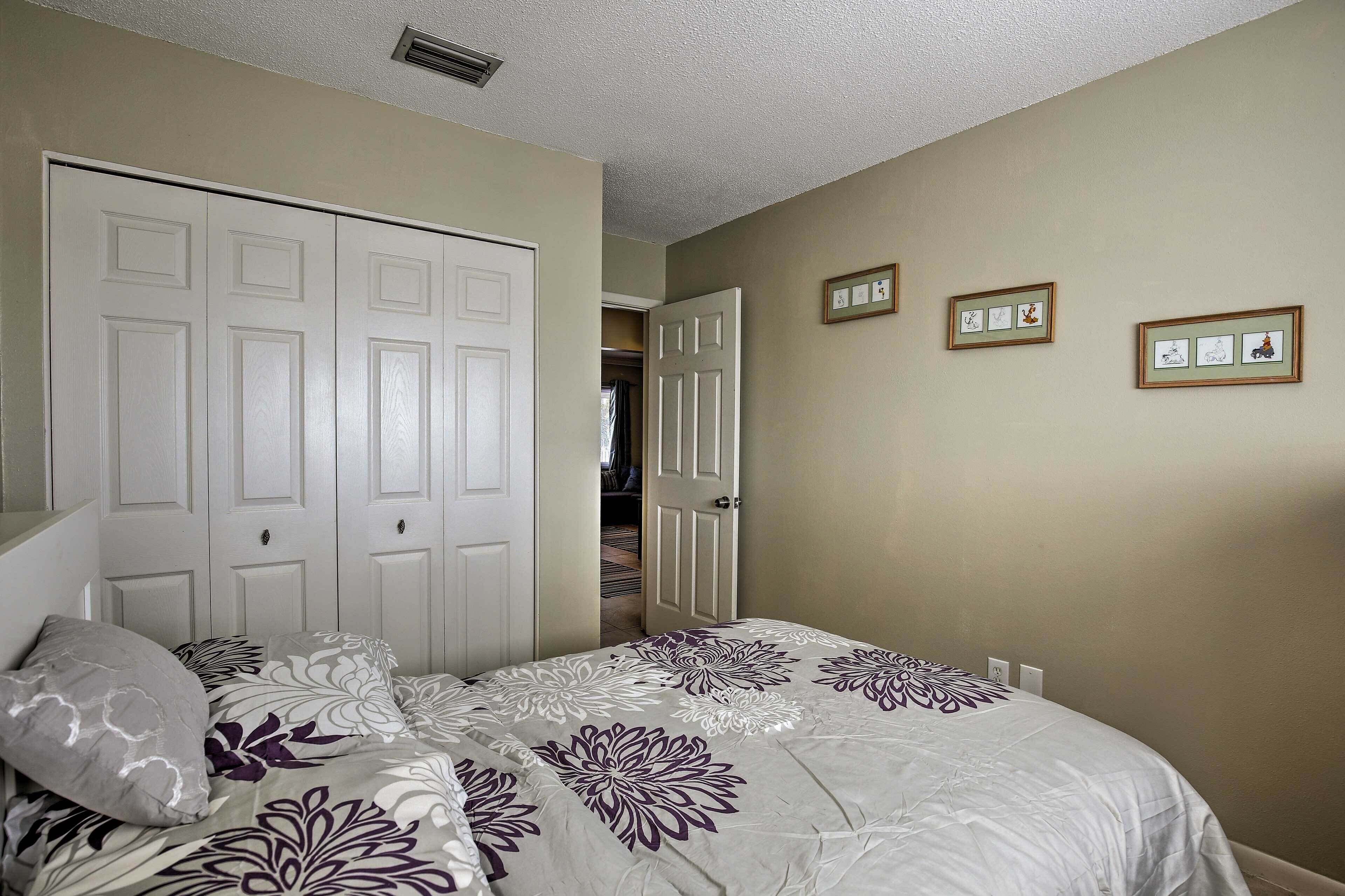 A bedroom with a bed, a wardrobe, and two framed pictures on the wall.