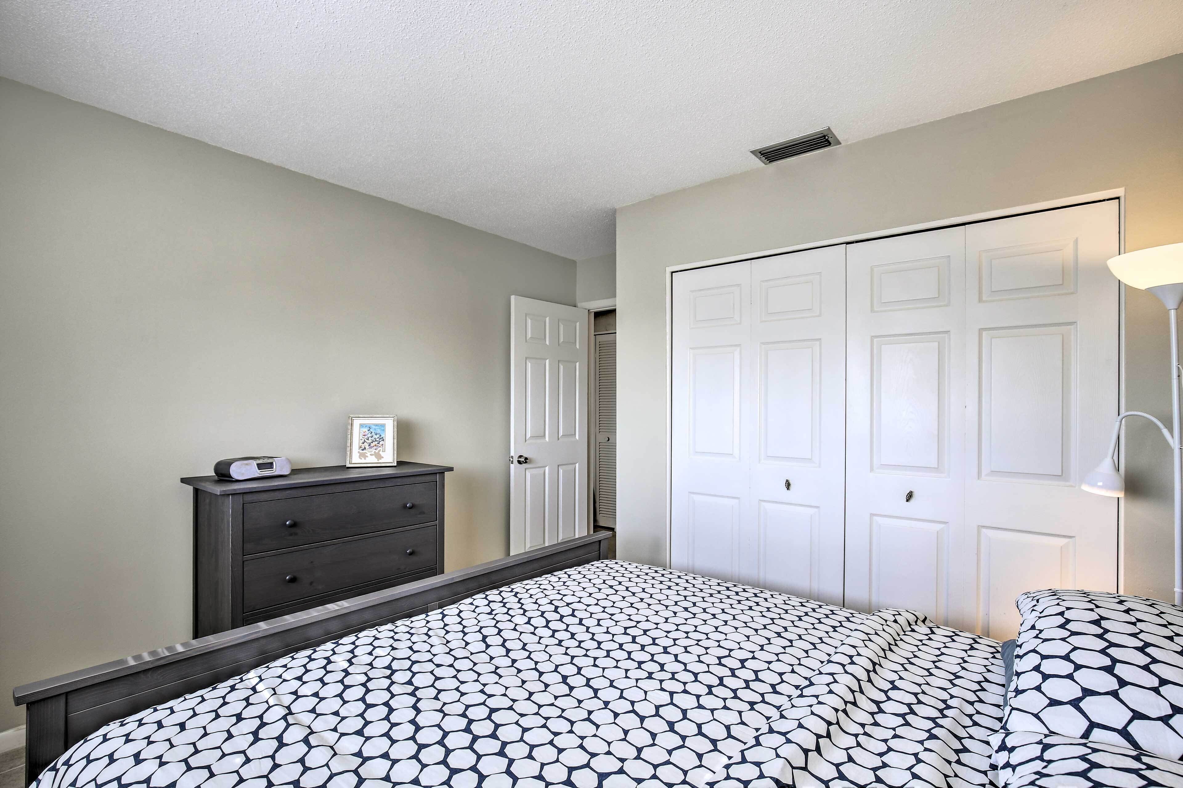 A bedroom with a bed, dresser, wardrobe, and bedside lamp.