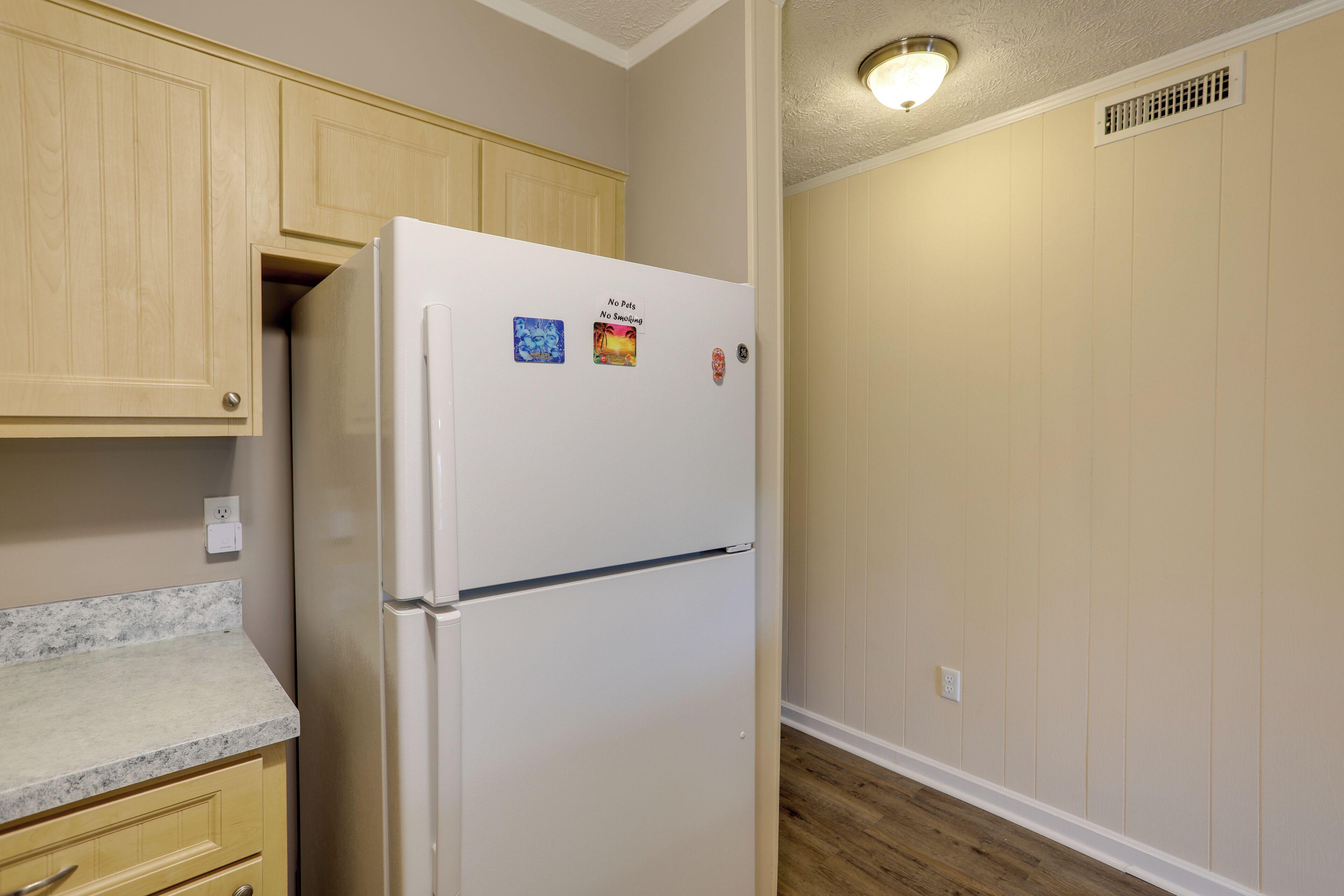 Una cocina con armarios de madera, un refrigerador blanco y una encimera de mármol.