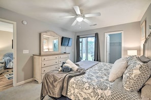 A bedroom with a bed, a dresser, a ceiling fan, a television, and a window with curtains. - True Blue Golf Resort Condo - 3 Mi to Beach! (Pawleys Island)