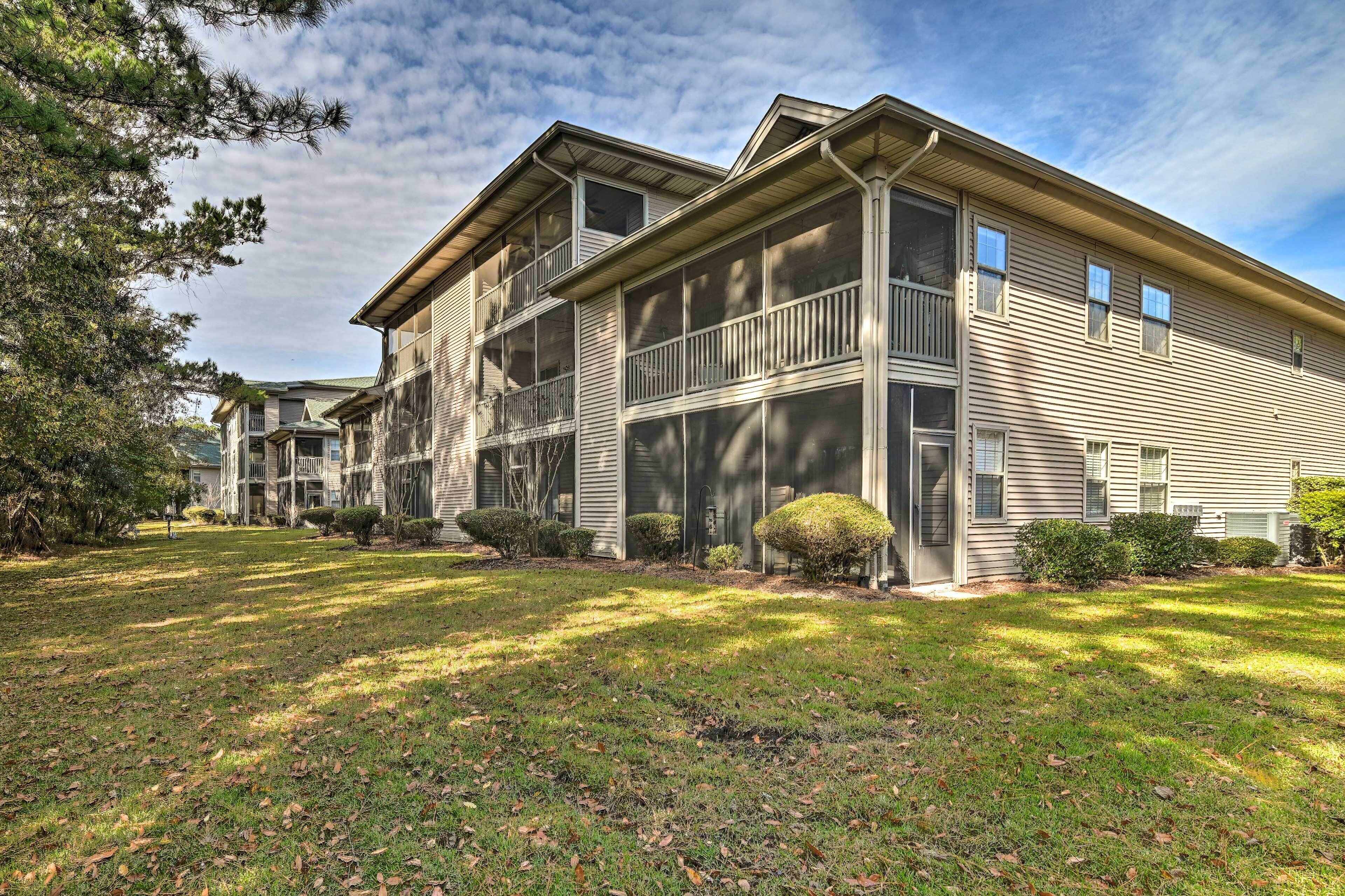 A two-story building with a balcony on the second floor, surrounded by a well-maintained lawn and trees.