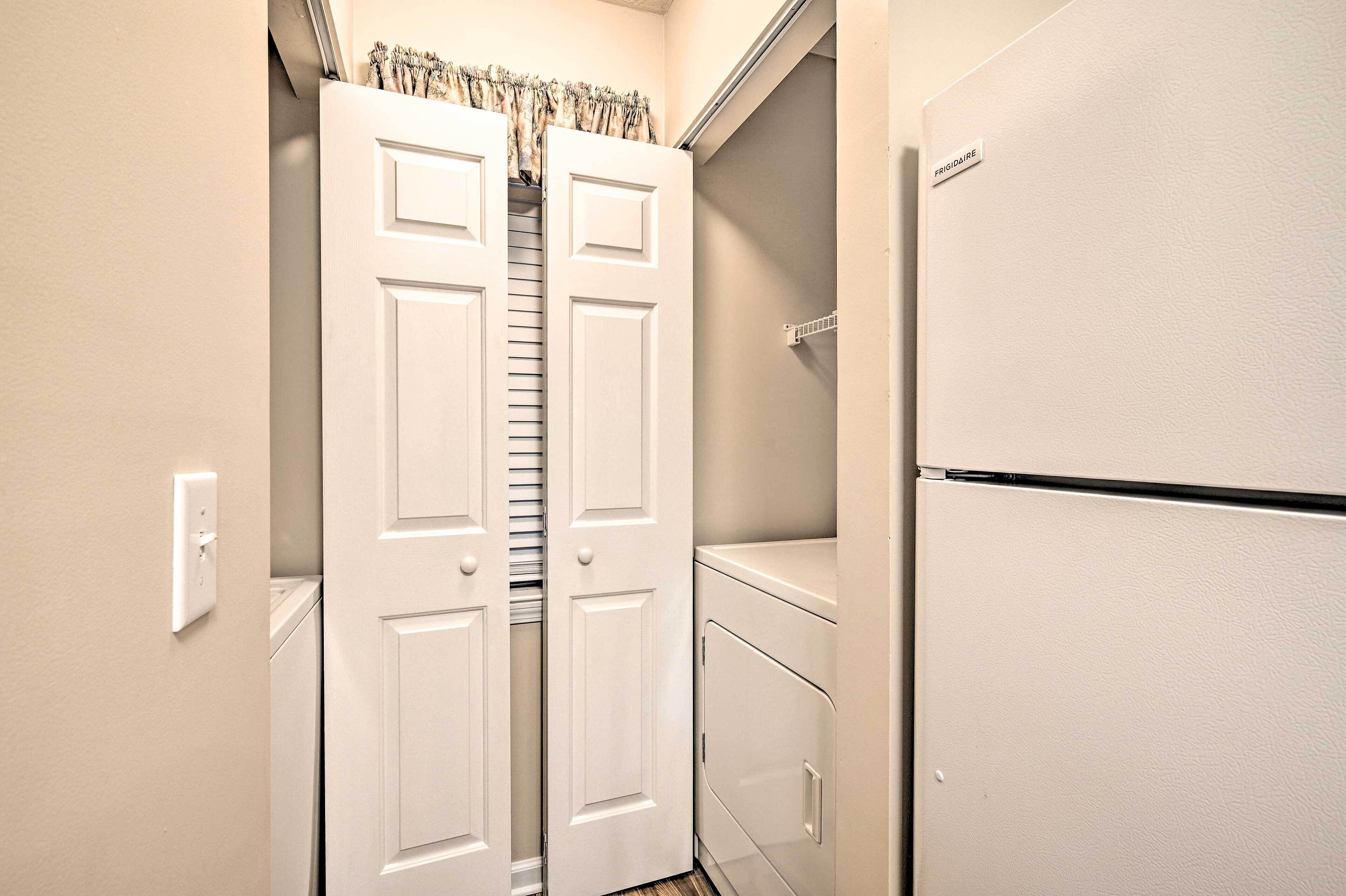 A compact kitchen with a white refrigerator, a pantry, and a double door closet with a curtain.