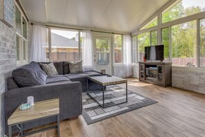 A modern living room with a sectional sofa, a coffee table, and a TV on a stand. - Sunny Pensacola Home w/ Fire Pit & Gas Grill! (Pensacola)
