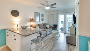 A modern kitchen with a granite countertop, white cabinets, and a ceiling fan. - Across the Street From Ocean: Surfside Beach Condo (Surfside Beach)