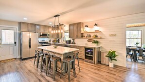 A spacious kitchen with a central island, bar stools, wooden cabinets, and a built-in wine cooler. - Townville Lake House w/ Private Dock, Kayaks! (Townville)