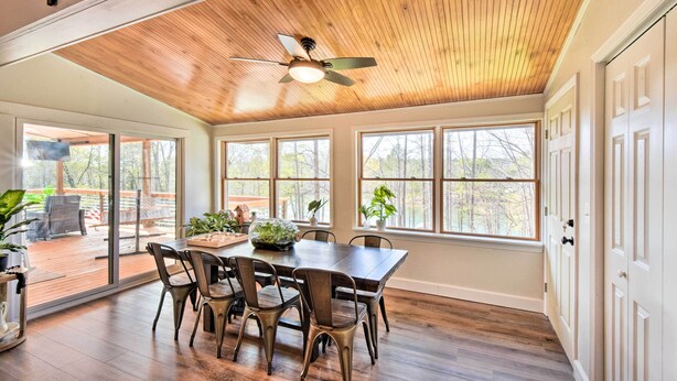 A spacious dining area with a wooden ceiling, large windows, and a view of the outdoor deck. - Townville Lake House w/ Private Dock, Kayaks! (Townville)