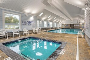 Un área de piscina con dos piscinas, sillas y señales de seguridad.