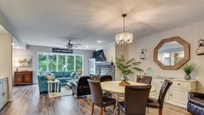 A spacious living area with a dining table, chairs, and a sofa. There is a sign on the wall that reads 'LAKE KEOWE'. - Lake Keowee Resort Condo w/ Fantastic View (Salem)