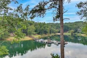 Ein ruhiger See mit anlegenden Booten, umgeben von dichtem Wald und blauem Himmel.