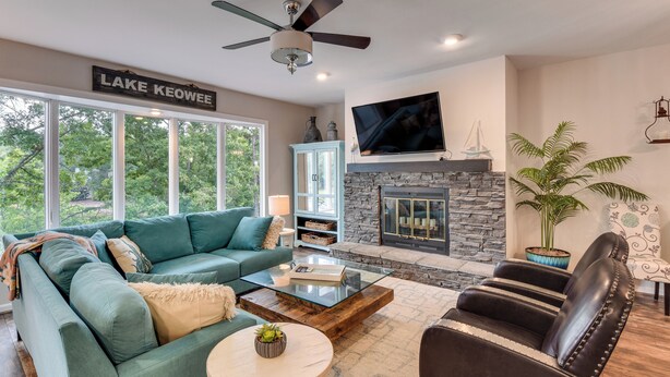 A modern living room with a green sofa, a leather armchair, a fireplace, and a television mounted on the wall. - Lake Keowee Resort Condo w/ Fantastic View (Salem)