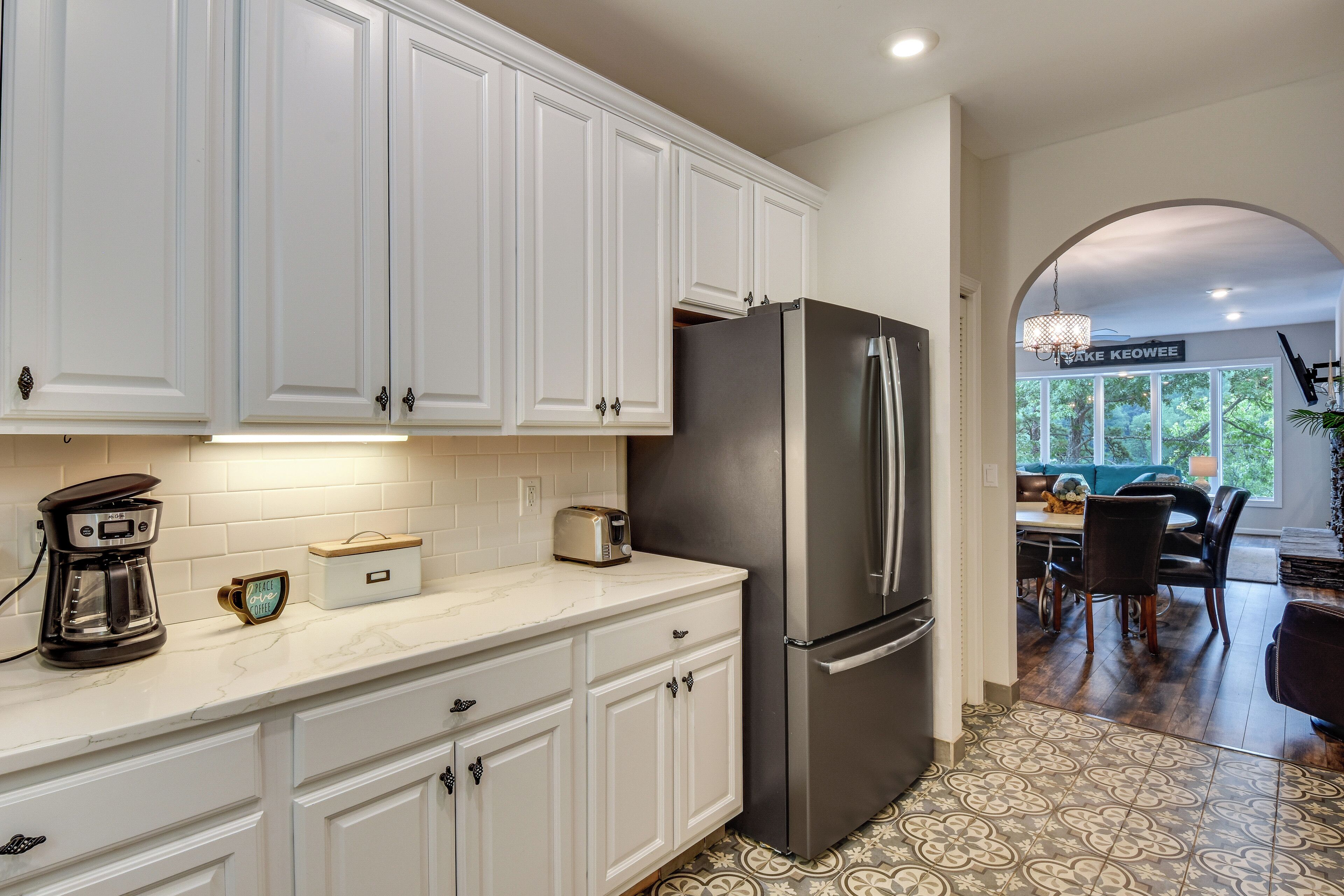 A kitchen with white cabinets, a stainless steel refrigerator, a coffee maker, and a toaster.