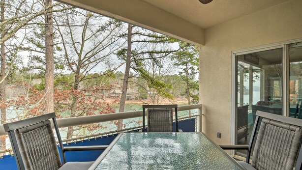 A balcony with a glass table and wicker chairs, overlooking a lake and trees. - Lake Keowee Resort Condo w/ Fantastic View (Salem)