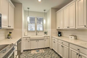 A kitchen with white cabinets, a stainless steel stove, a sink, and a window with blinds. - Lake Keowee Condo With Fantasitic View and Resort (Salem)