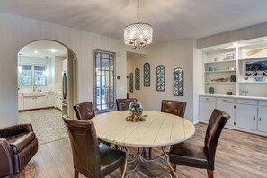 A dining area with a round table, chairs, and a chandelier.