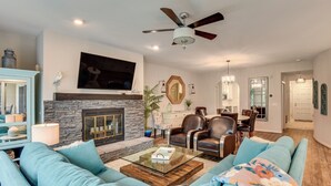 A living room with a stone fireplace, a ceiling fan, and a television mounted on the wall. - Lake Keowee Resort Condo w/ Fantastic View (Salem)