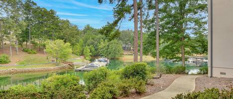 A lakeside view with boats docked, surrounded by dense trees and a clear sky.